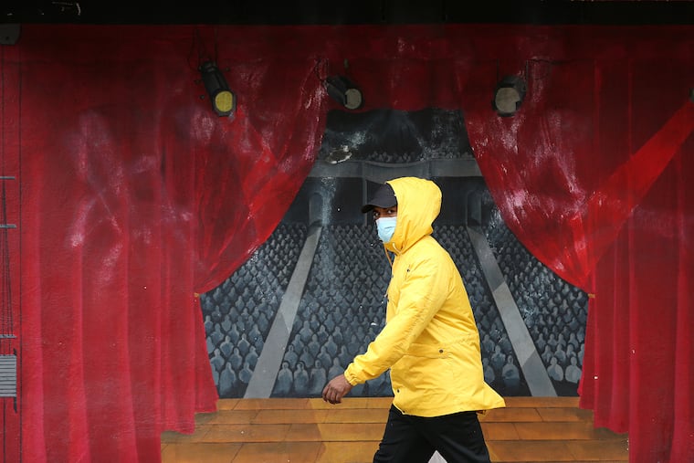 A pedestrian, who didn’t want to give his name, passes a mural at the Philadelphia Theatrical Supply shop last week.