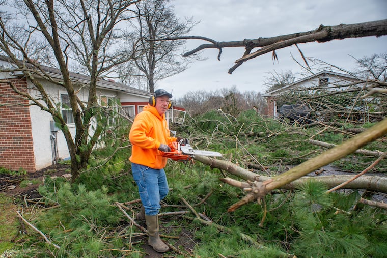 Paul Burger helps remove tree debris from his daughter and son-in-law’s home in Bedminster Township, Bucks County, on Friday.