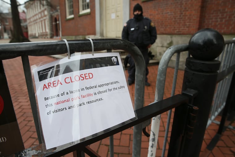 A private security guard stands near a sign noting the closure of Independence Hall in Philadelphia on Saturday, Dec. 22, 2018.