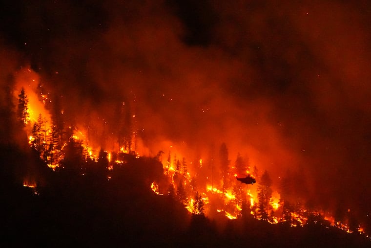 FILE - A helicopter conducting night operations prepares to drop water on the Quilpituk Creek wildfire burning on the west side of Okanagan Lake near Fintry, British Columbia, Aug. 3, 2026. (Darryl Dyck/The Canadian Press via AP, File)