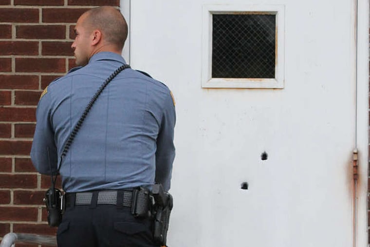 A West Deptford officer opens the bullet-riddled side door of the town's police station. No one was injured in the attack on the building.