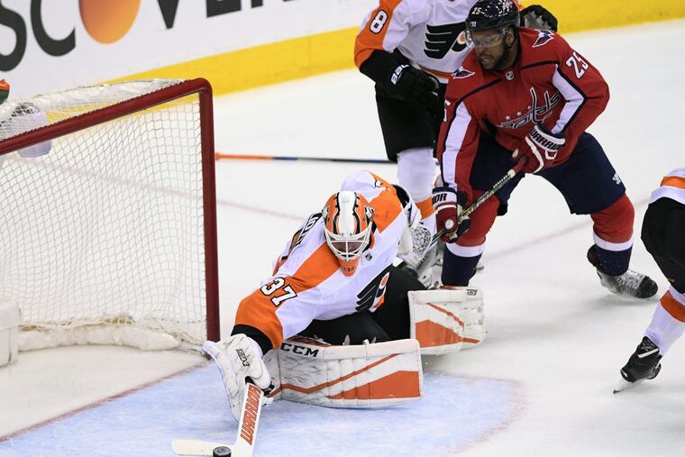 Goaltender Brian Elliott knocks the puck away from Washington’s Devante Smith-Pelly during the third period of the Flyers’ 2-1 overtime win Sunday.