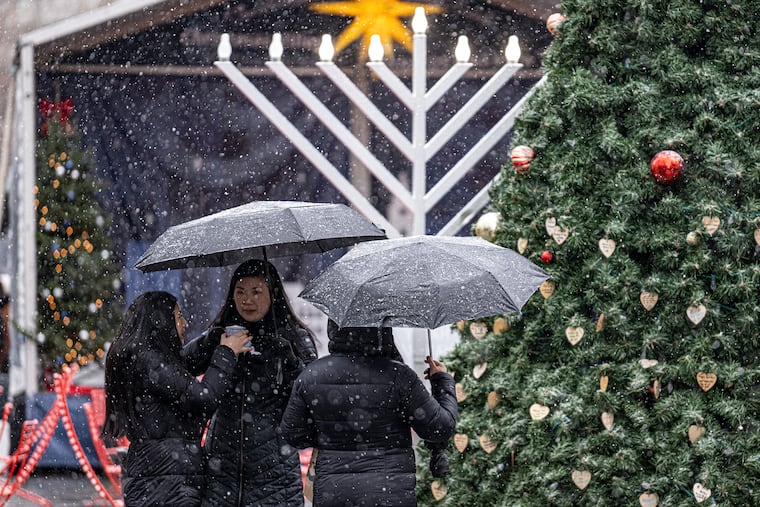 Shoppers shield from the snow right before Christmas, the last time that any flakes were sighted in Philly.