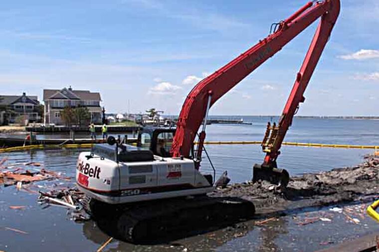 A crane removes the last remains of a house that had washed into the Barnegat Bay in Mantoloking, N.J. on Friday, May 10, 2013. The town that was devastated by Superstorm Sandy is demolishing the first of 50 storm-wrecked homes that need to be taken down. (AP Photo/Wayne Parry)