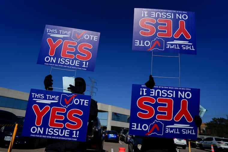 People hold signs urging a vote for a constitutional amendment seeking to protect abortion rights in Ohio in the parking lot of the Hamilton County Board of Elections in Cincinnati.