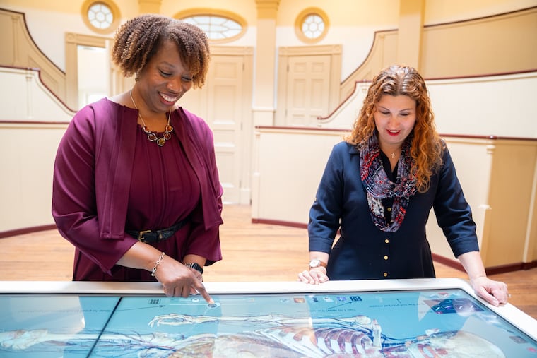Pennsylvania Hospital CEO Alicia Gresham and lead archivist Stacey Peeples test out the life-size 3D touch-screen table in the surgical amphitheater.