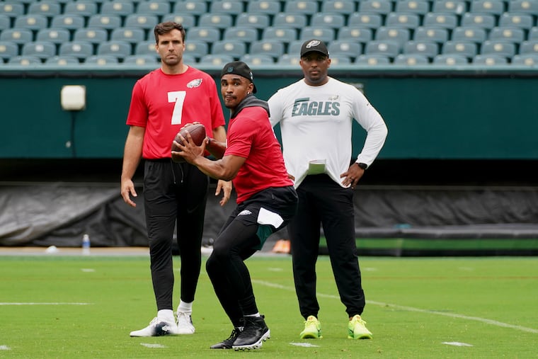 Quarterbacks coach Brian Johnson (right) watches quarterback Jalen Hurts during practice last week. At left is Joe Flacco.