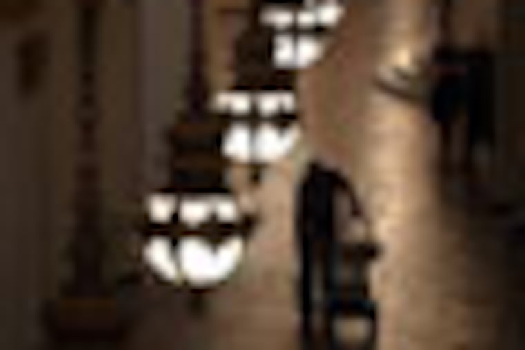 PJOURNAL01B, 4/14/04, photo by Laurence Kesterson, Harrisburg, Pa. IN THIS PHOTO: A capitol worker pushes a dolly down the east hallway of the capitol building on a Moravian tile floor designed by Henry Mercer of Doylestown. The hanging lights were designed by Philadelphia architect Joseph Huston. THE STORY: A view of the art in the state capitol building on the 100th anniversary of the laying of the cornerstone on May 5. 2 of many