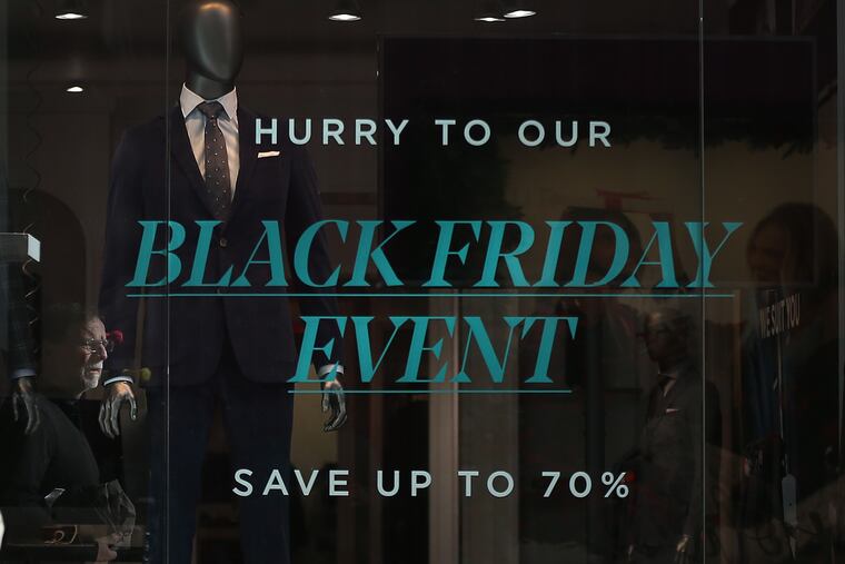 A shopper is reflected in a window of the Indochino shop at the King of Prussia Mall this week as stores prep for the busiest shopping day of the year.