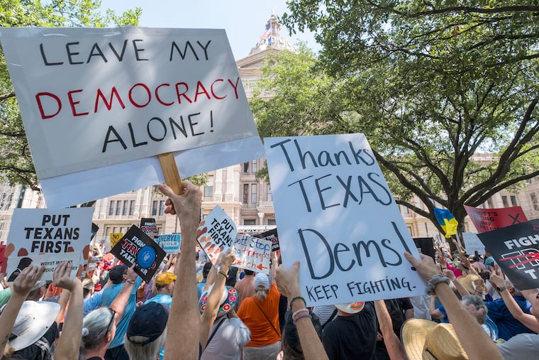 Protesters hold up signs during the "Fight the Trump Takeover" rally held at the Texas Capitol on Saturday in Austin, Texas, to protest congressional redistricting efforts by Texas Republicans and President Donald Trump.