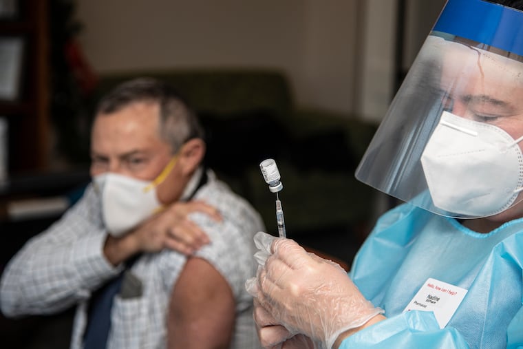 Pharmacist Nadine M. Mackey (right) prepares a COVID-19 vaccine for Dr. Gary Bernett at Power Back Rehabilitation in Phoenixville on Dec. 28, as nursing homes in Pennsylvania and New Jersey began to distribute vaccines.