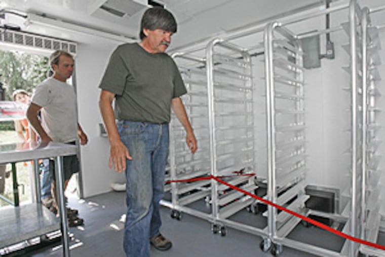Pete Johnson, owner of Pete's Greens, left, gets a tour from Brian Norder of a new state Agency of Agriculture mobile freezing unit in Craftsbury, Vt. Johnson already extends his vegetable farm's summer bounty by using cold storage. Now, he'll be able to quick-freeze some of his crop, allowing him and other farmers to offer customers more through the year.