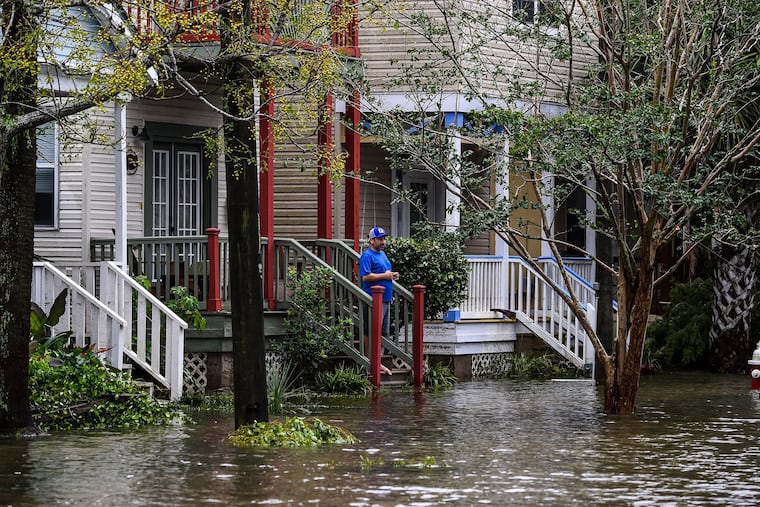 A man, standing outside of his home, watches a street flooded by Hurricane Sally in Pensacola, Fla., last month.