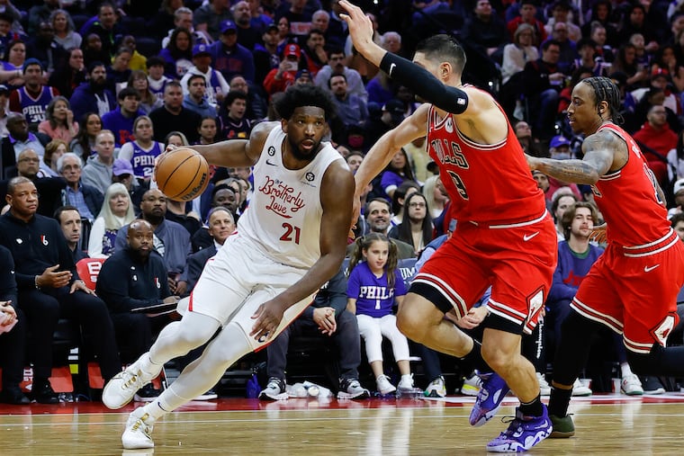 Sixers center Joel Embiid dribbles the basketball against Chicago Bulls center Nikola Vucevic and forward DeMar DeRozan on Monday, March 20, 2023 in Philadelphia.