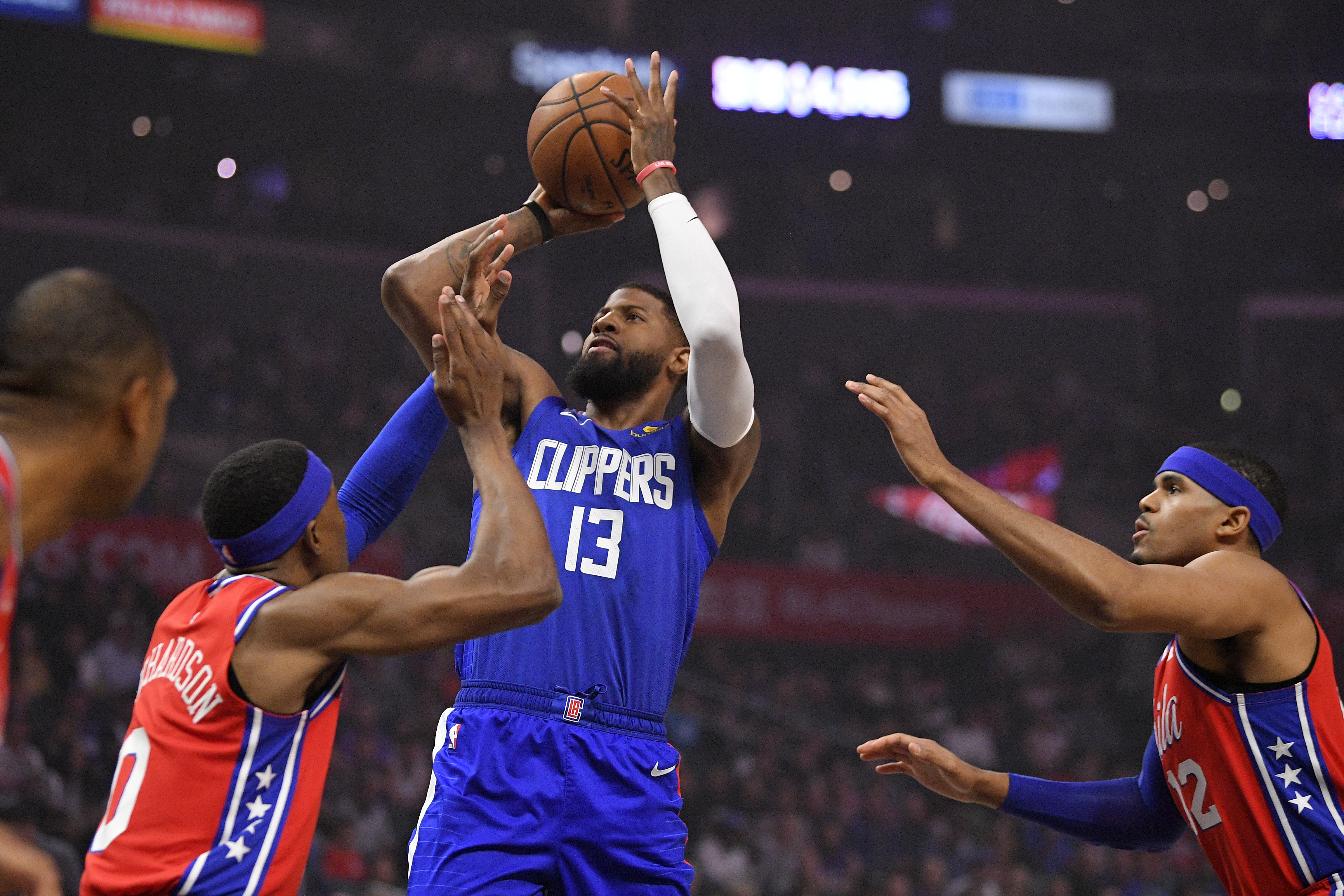 Clippers guard Paul George shoots as 76ers guard Josh Richardson, left, and forward Tobias Harris defend during the first half.