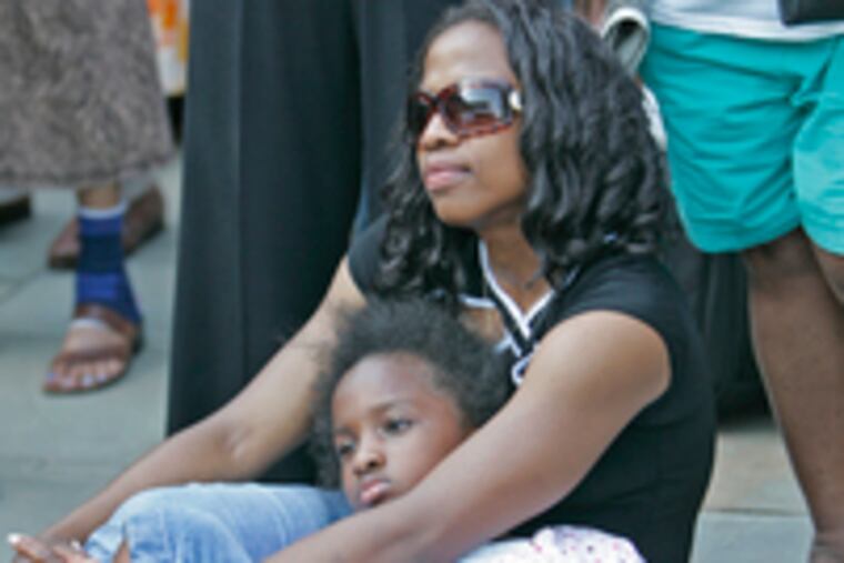 Myara Clark holds her daughter 8-year-old daughter, Kyra, as they listen to the presentation. "My ancestors hated every second of slavery," actor Darrell Lee told the gathering.