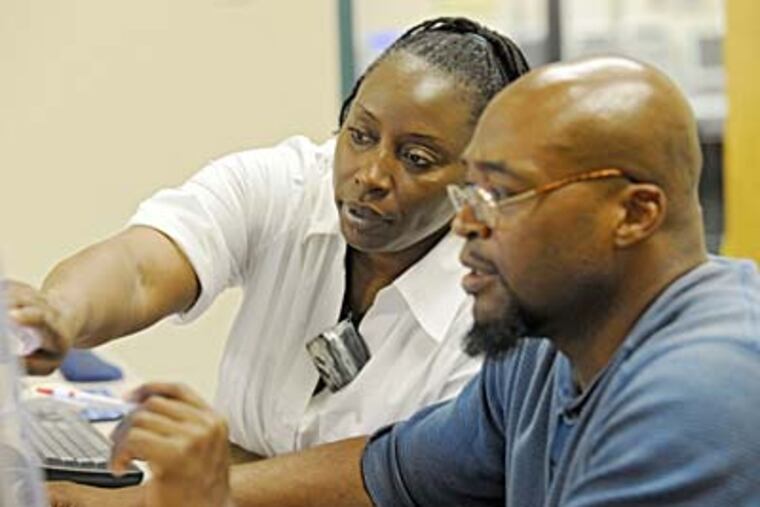 Lisa Carstarphen helps fellow job seeker Ali Johnson use a computer at the Camden County workforce center.. (CLEM MURRAY / Staff Photographer)