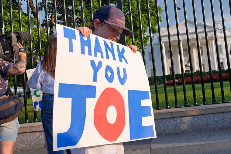 Hugh Kieve, 10, of Washington, holds a sign outside the White House as he and his family come out to show support for President Joe Biden.
