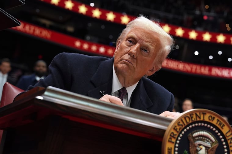 President Donald Trump signs an executive order as he attends an indoor Presidential Inauguration parade event at Capital One Arena, Monday.