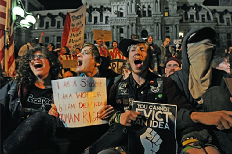 Linking arms in anticipation of arrest at Dilworth Plaza are (from left) Diane Isser; Brianna Murphy; Shawn Grant; and, hidden by a scarf, Barry Cade. (APRIL SAUL / Staff Photographer)