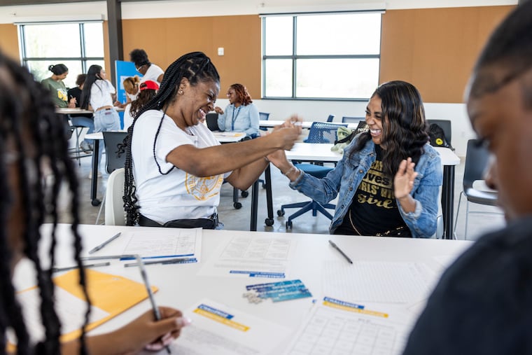 Girls High students Saniyah Brown and Kyla Graves celebrate being the first team to finish a time management challenge at the new TGR Learning Lab in West Philadelphia. The center, part of a $180 million project, was funded in part by Tiger Woods' foundation.