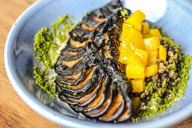 Whole eggplant cooked over the coals at Zahav is served as a vegan option over freekeh, lentils and pistachios topped with mangos pickled in amba sauce.