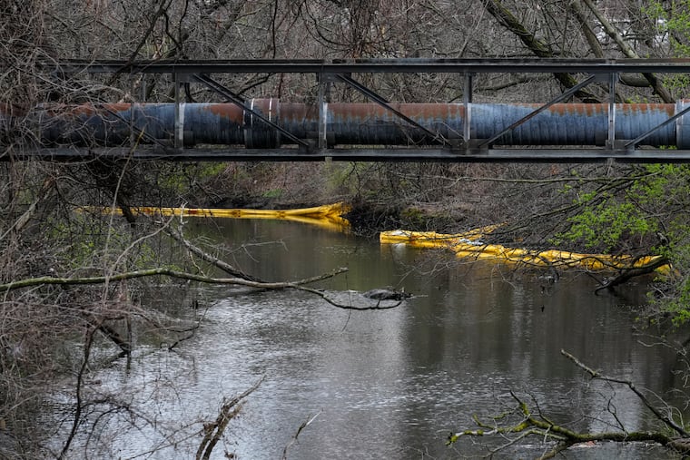 Following a chemical spill, booms extend along the banks of Otter Creek in Bristol, Pa., Tuesday, March 28, 2023.