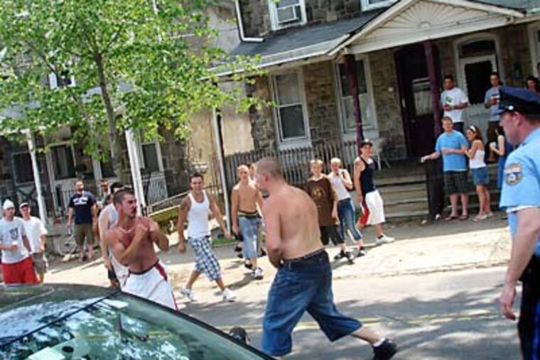 Two men duke it out in the middle of Manayunk Avenue at the end of the bike race on June 8, 2008, as a police officer prepares to break up the fight. Residents have cited similar problems at the event in recent years. (Vance Lehmkuhl / Philly.com)