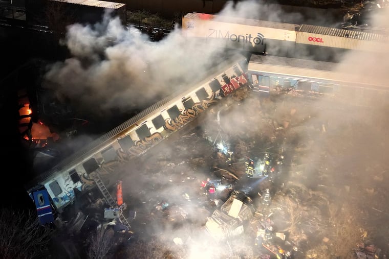 Smoke rises from trains as firefighters and rescuers operate after a collision near Larissa city, Greece, early Wednesday.