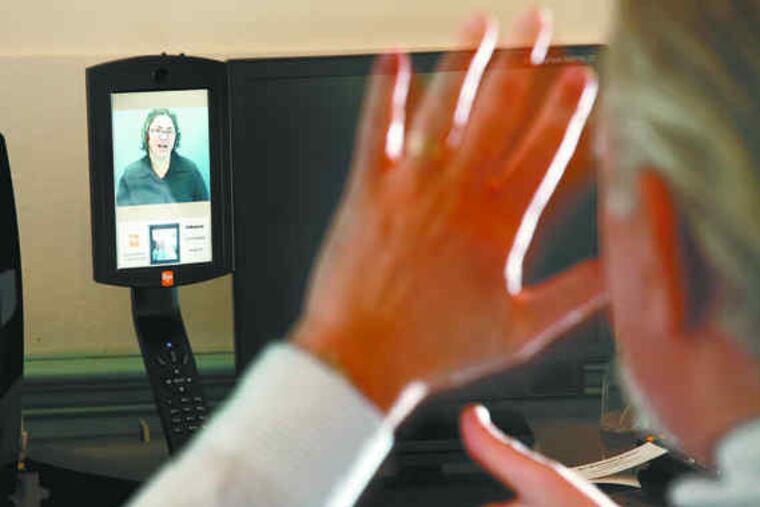 Larry Taub makes a phone call on a videophone, which allows users to communicate with a relay center through sign language.