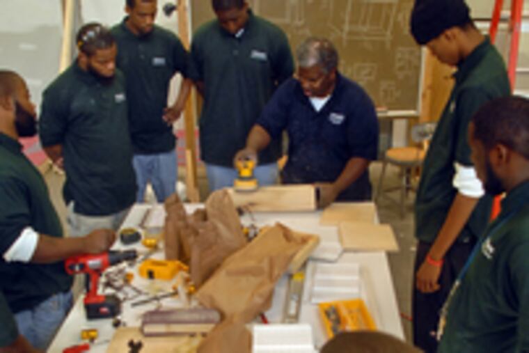 Jerome Henry demonstrates how to use a sander. About one-third of the students in his carpentry class are ex-offenders, and they show a lot of hustle in class, he said.