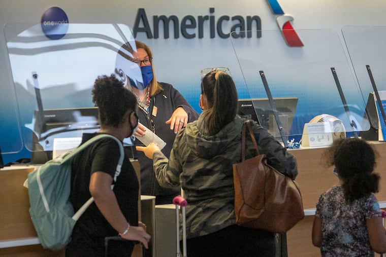 An American Airlines employee attends to travelers at Philadelphia International Airport on Nov. 11, 2020. The company said it could furlough more than 1,000 Philadelphia-based workers in April because of the pandemic's effect on business.