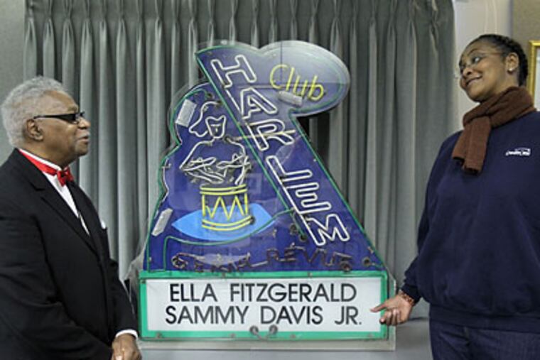 Exhibit organizer Ralph Hunter with Nancy Martin, who was a cocktail server, with the original neon sign. (DAVID M WARREN / Staff Photographer)