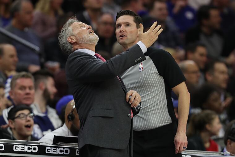 Sixers coach Brett Brown, left, watches a replay as he complains about a lane violation on a free throw during the second half against Cleveland.