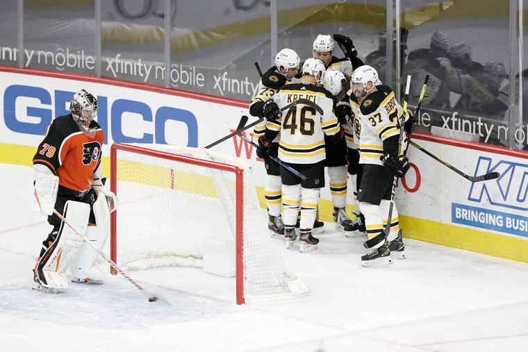 Carter Hart gets the puck out of the net while the Bruins celebrate after tying the game at 3-3 late in the third period.
