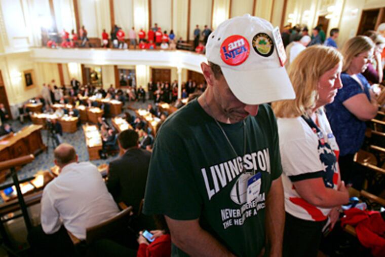 Members of the gallery turn their backs on the Assembly floor in protest as the State Assembly debate befores voting on the employee benefits bill in at the State House in Trenton on Thursday. (Rich Schultz / Associated Press)