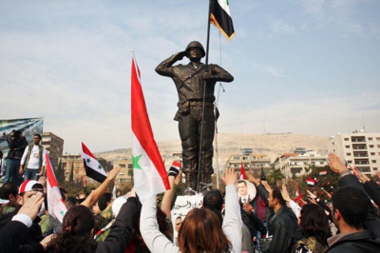 Pro-regime demonstrators rally around a statue of a soldier at Umayyad Square in Damascus. Syrian troops reportedly surrounded a valley Tuesday and killed 110 people. (Bassem Tellawi / Associated Press)