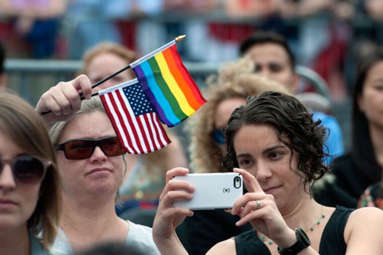 Sandy Mayson takes a photo of a rainbow flag and an American flag held by wife Maron Deering during the National LGBT 50th Anniversary ceremony in front of Independence Hall on July 4, 2015. (CLEM MURRAY/Staff Photographer)