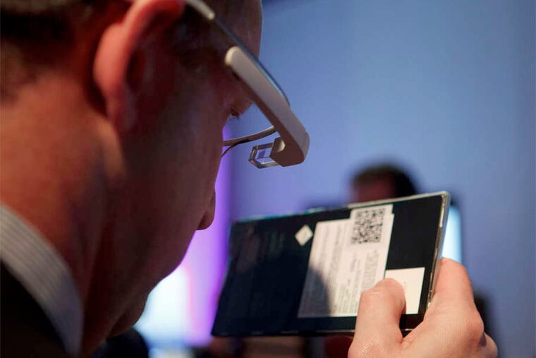 At a tech convention this year, an employee, left, shows how Google Glass- connected glasses can read barcodes.