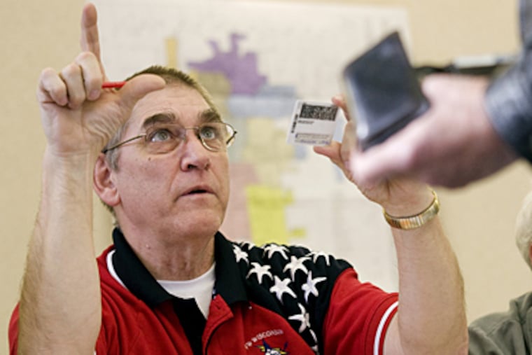 John Kleinmaus of West Bend instructs a voter of the district boundaries while reviewing his drivers license at the West Bend Library on Feb. 21, 2012 in West Bend, Wis. Wisconsin residents who voted Tuesday were subject for the first time to the state's voter I.D. laws. (AP Photo/West Bend Daily News, John Ehlke)