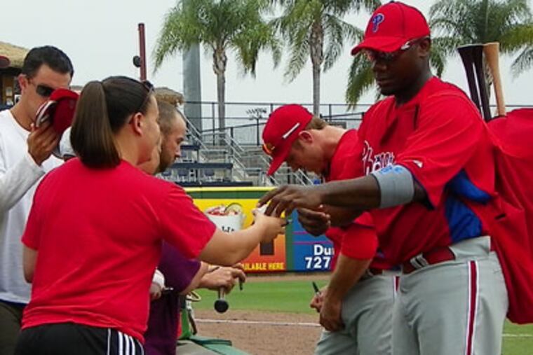 Ryan Howard and Chase Utley sign autographs for fans following an extended spring training game. (Photo by Eddie Michels)