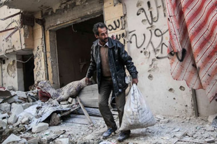 In this Sunday, Dec. 2, 2012 photo, a man collects his belongings after his home was damaged due to heavy fighting between Free Syrian Army fighters and government forces in Aleppo, Syria. (AP Photo/Narciso Contreras)