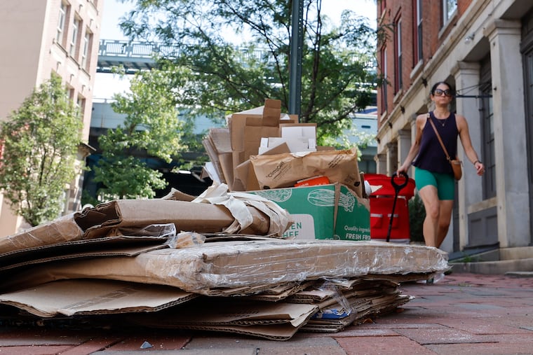 A pedestrian walks near uncollected recycling items along the 200 block of North Third Street in Old City on Monday.