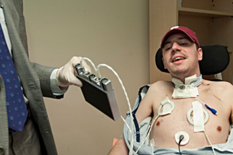 Kevin Neary looks at the device, held by Dr. Matthew Kaufman, that
lets him breathe without a ventilator. CLEM MURRAY / Staff Photographer