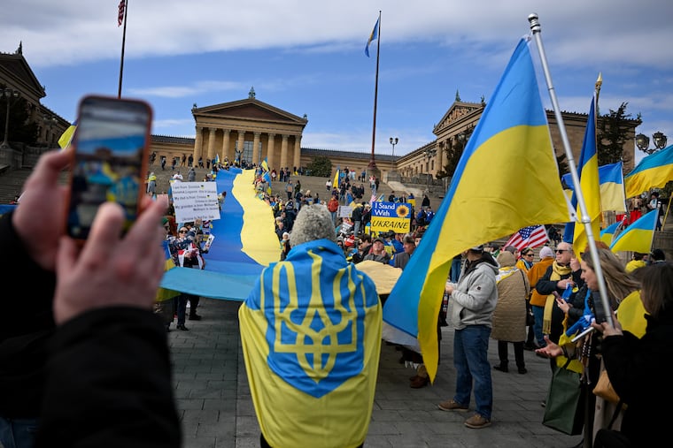 A large Ukrainian flag is unfurled on the art museum steps Sunday, Mar, 1, 2026 as people standing with Ukraine at a previously scheduled, but snow storm-delayed, rally marking the fourth anniversary of the Russian war.