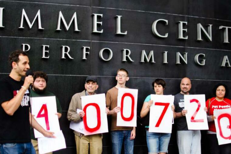 Protesters outside the Comcast shareholders meeting at the Kimmel Center hold signs indicating the number of people who they say oppose the Comcast/Time Warner Cable deal. (Viviana Pernot / Staff Photographer)