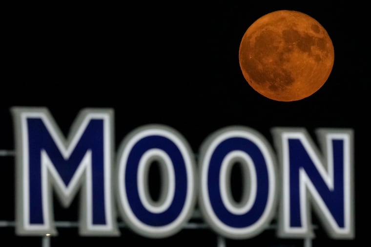 A supermoon rises beyond a beer sign at Kauffmann Stadium during a baseball game between the Kansas City Royals and the New York Mets, Aug. 1, 2023, in Kansas City, Mo.