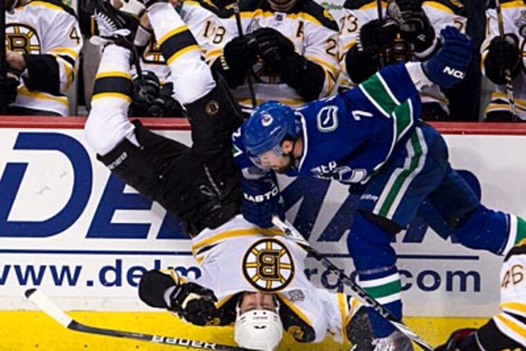 The Bruins' Milan Lucic is upended by the Canucks' Dan Hamhui. (AP Photo/The Canadian Press, Jonathan Hayward)