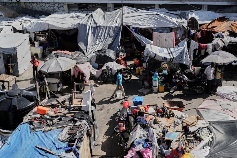 A man carries a buckets of water where families displaced by gang violence are living in Port-au-Prince, Haiti, Wednesday, Aug. 12, 2026. ICE on Thursday deported 170 Haitians who had lost TPS status back to their homeland.