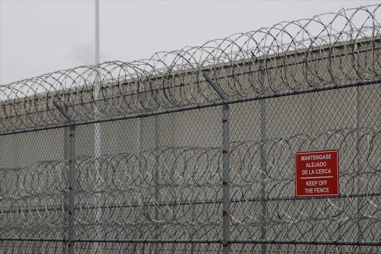Barbed wire fencing is shown behind a sign in English and Spanish in a recreation yard used by detainees during a media tour of the U.S. Immigration and Customs Enforcement detention center, Dec. 16, 2019, in Tacoma, Wash.